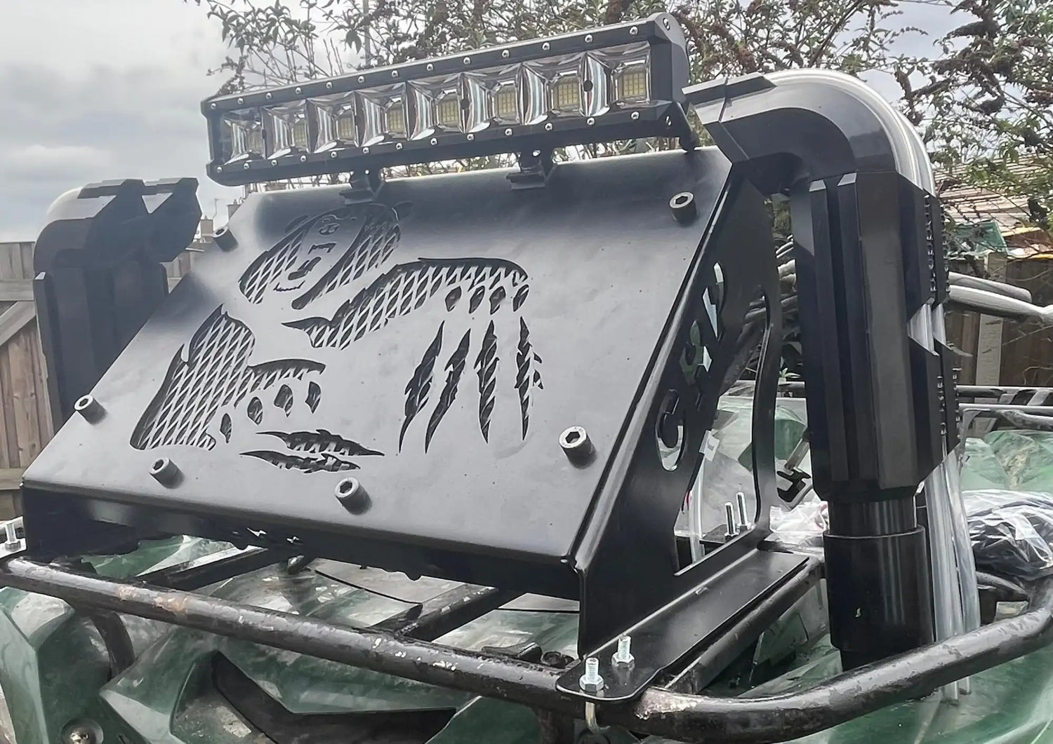 Black metal roof rack with laser-cut dinosaur and claw patterns, mounted above a vehicle.