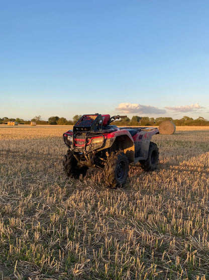 Red and black honda foreman atv with heavy-duty radiator relocation kit parked in a harvested field