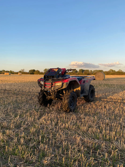 Red and black honda foreman atv with heavy-duty radiator relocation kit parked in a harvested field
