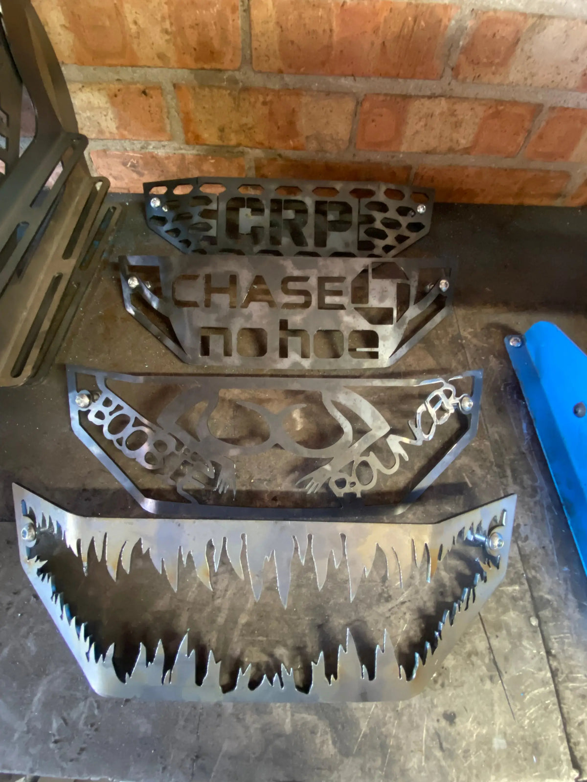 Black metal front fender guards with engraved brand names and aggressive tooth-like cutouts for honda trx 420 grille cover