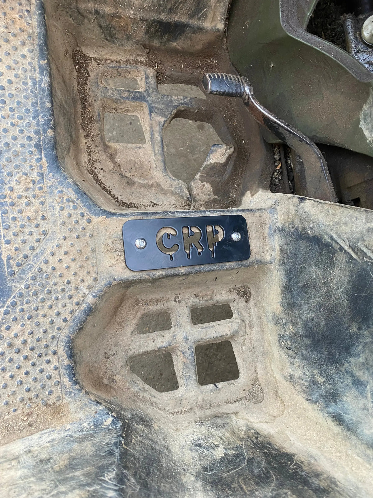 Black metal heavy-duty flat footpegs with crp engraved in dripping font mounted on rugged honda trx floor