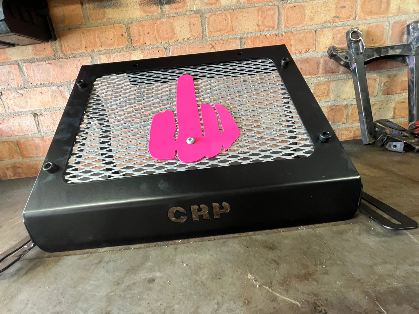 Black metal fire pit with pink plastic hand gesture emblem on mesh grate for Kawasaki Brute Force 750 radiator kit