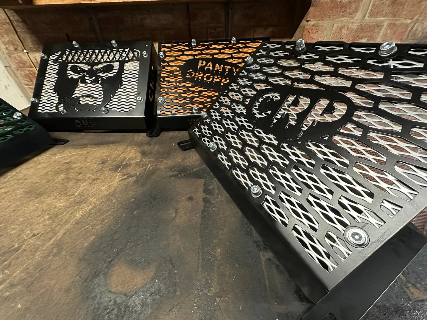 Black metal heavy-duty radiator relocation kit with intricate cut-out designs and panty drop lettering for Yamaha Grizzly 550 700