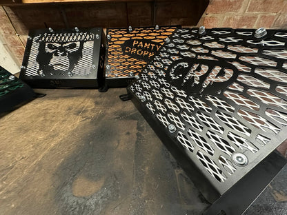 Black metal heavy-duty radiator relocation kit with intricate cut-out designs and panty drop lettering for Yamaha Grizzly 550 700