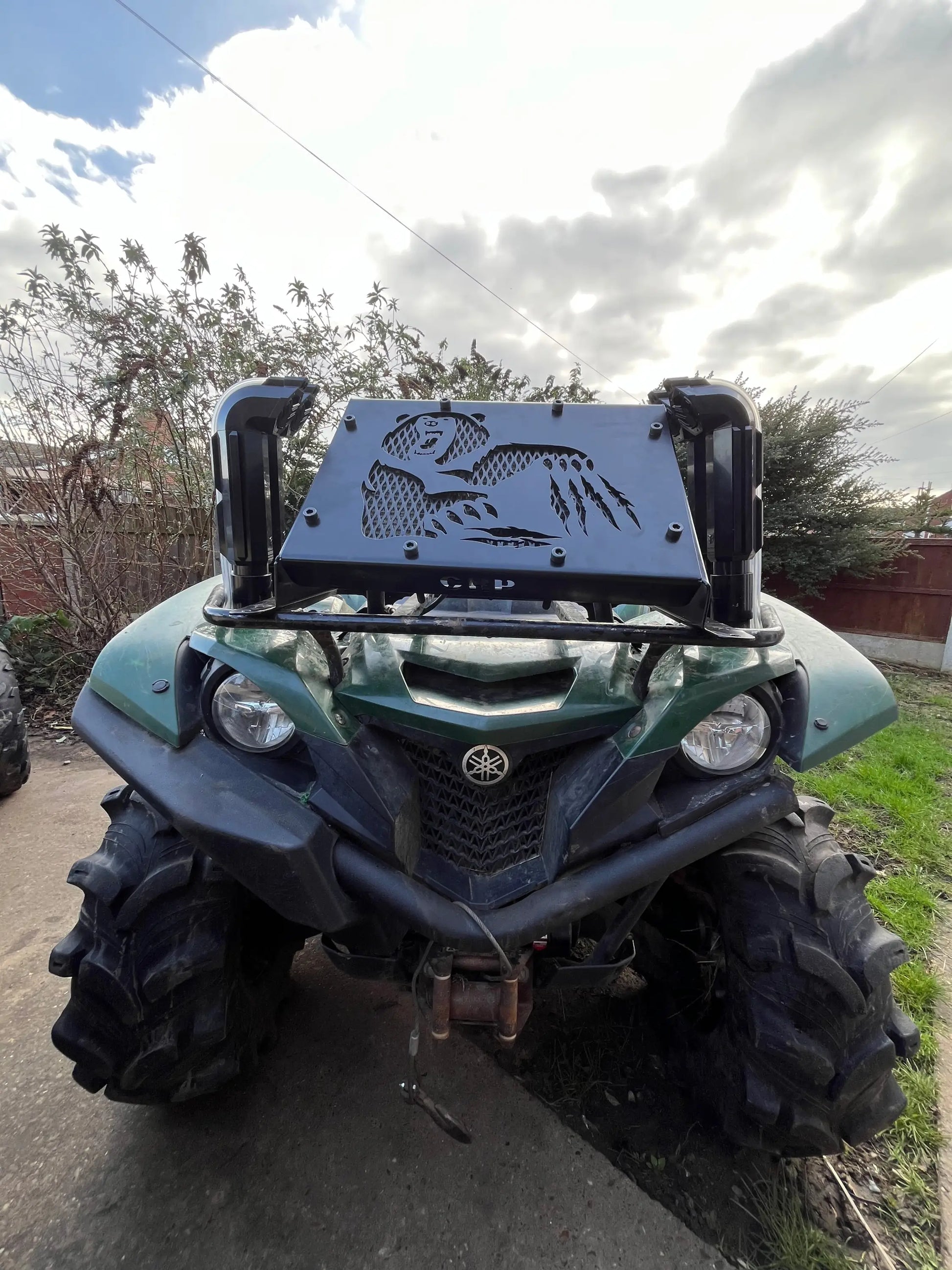 Black metal front guard with engraved fish and mountain design mounted on green yamaha grizzly kodiak 700 atv